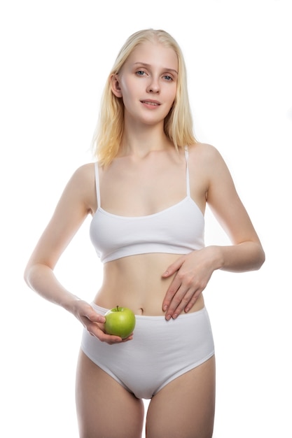 Retrato de mujer sonriente atractiva con manzana en la pared blanca.