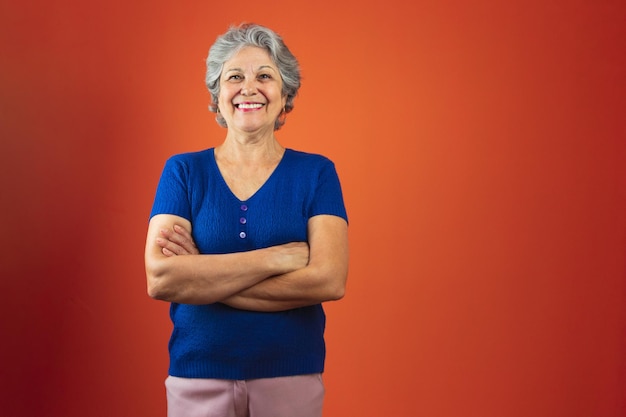 Retrato de mujer sonriente con cabello gris y camiseta azul aislado sobre fondo naranja