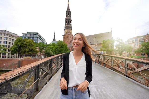 Retrato de mujer sonriente caminando sobre el puente en la ciudad de Hamburgo, Alemania