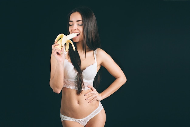 Retrato de mujer sonriente caucásica atractiva comiendo plátano.