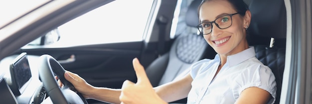 El retrato de una mujer sonriente conduciendo un auto nuevo muestra su aprobación comprando un nuevo concepto de auto