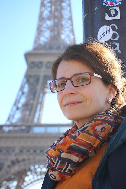 Foto retrato de una mujer sonriente contra la torre eiffel