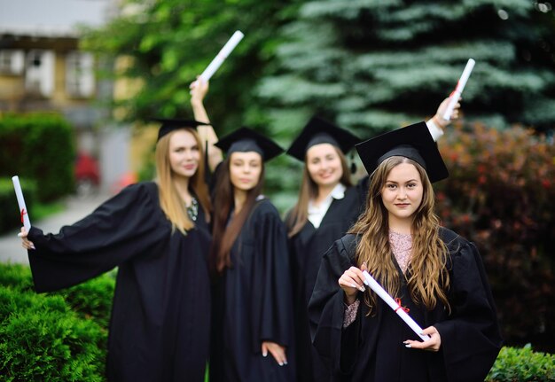 Foto retrato de una mujer sonriente con un diploma de pie frente a sus amigos