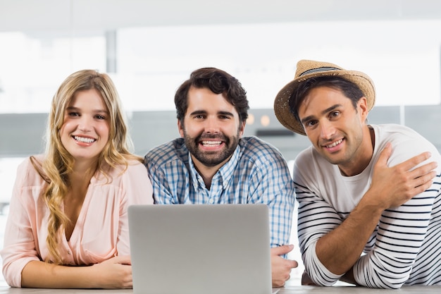 Retrato de mujer sonriente y dos hombres usando laptop