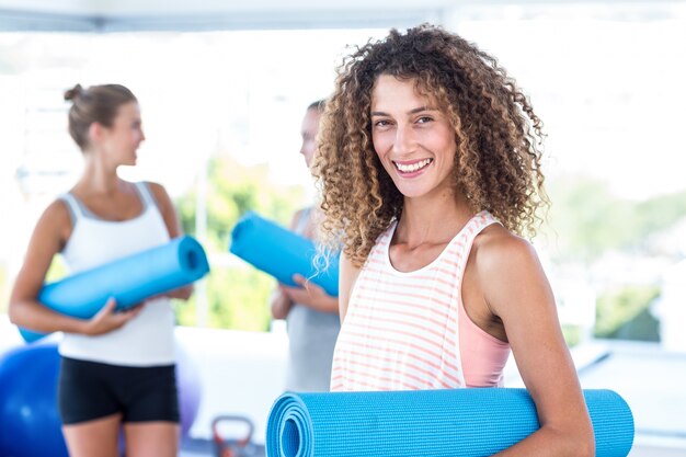 Retrato de mujer sonriente con estera de yoga