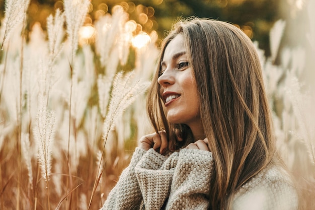 Retrato de una mujer sonriente feliz en otoño en el campo. Ella mira hacia adelante.