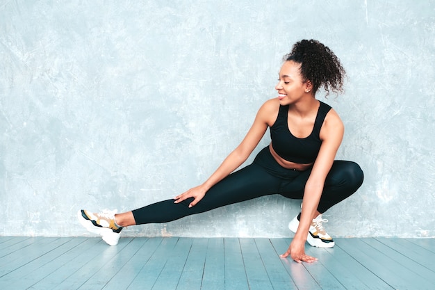 Retrato de mujer sonriente fitness en ropa deportiva con peinado de rizos afro