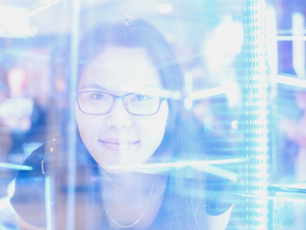 Retrato de una mujer sonriente con gafas visto a través de una ventana de vidrio