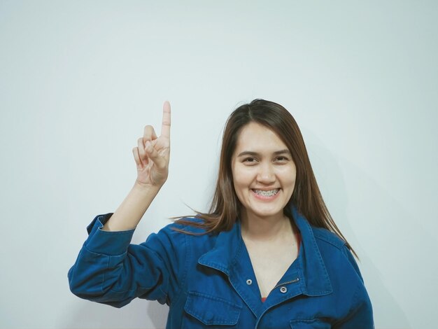 Foto retrato de una mujer sonriente gestando mientras está de pie contra un fondo blanco