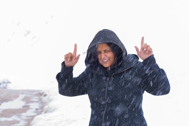 Foto retrato de una mujer sonriente gestando mientras está de pie en la nieve