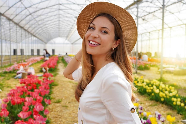 Foto retrato de mujer sonriente gira y mira a la cámara caminando entre tulipanes