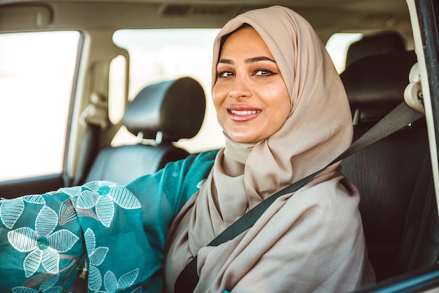 Retrato de una mujer sonriente con hijab sentada en un coche