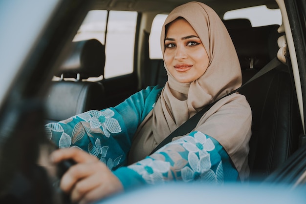 Retrato de una mujer sonriente con hijab sentada en un coche