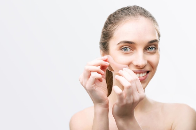 Retrato de mujer sonriente sin maquillaje pega parches rosas debajo de los ojos