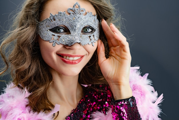 Foto retrato de una mujer sonriente en máscaras de carnaval mirando el primer plano de la cámara