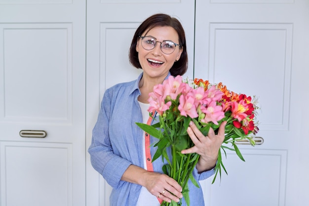 Retrato de una mujer sonriente de mediana edad con un ramo de flores.