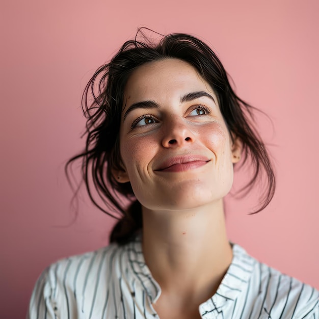 Foto retrato de una mujer sonriente mirando al cielo sobre un fondo rosa