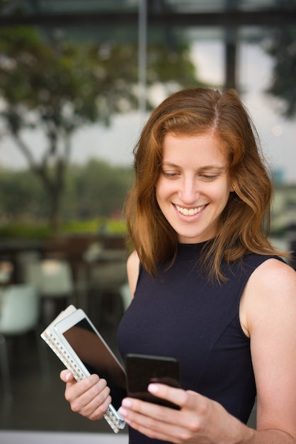 Retrato de mujer sonriente mirando la pantalla del teléfono