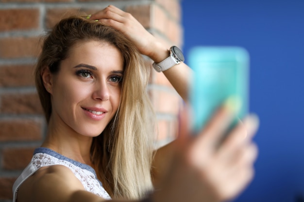 Retrato de mujer sonriente mirando smartphone con calma y alegría.