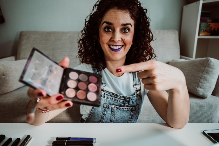 Foto retrato de una mujer sonriente mostrando la paleta de sombra de ojos