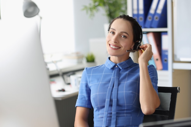 Retrato de mujer sonriente operador en auriculares en el lugar de trabajo