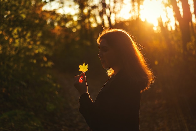 Retrato, de, mujer sonriente, en, otoño, parque, con, hoja amarilla