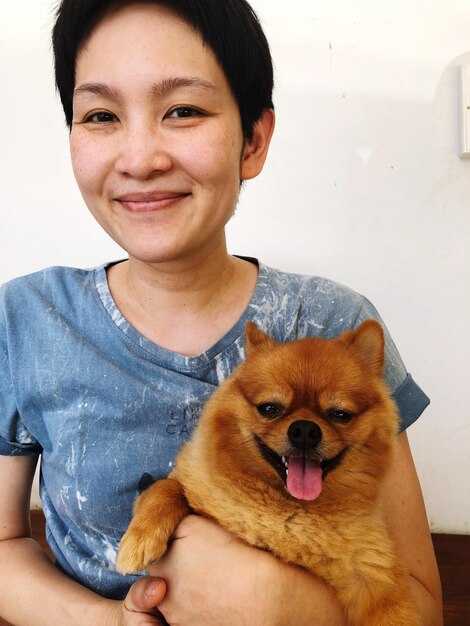 Foto retrato de una mujer sonriente con un perro en casa