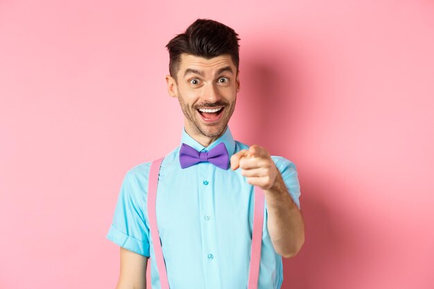 Retrato de una mujer sonriente de pie contra un fondo rosa