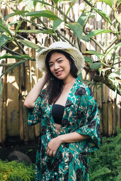 Foto retrato de una mujer sonriente de pie contra las plantas