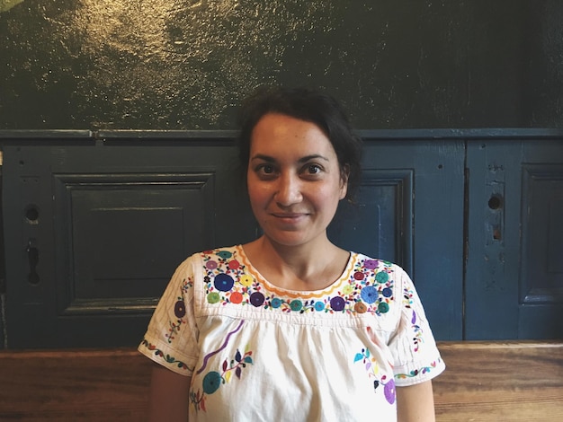 Foto retrato de mujer sonriente de pie contra la puerta