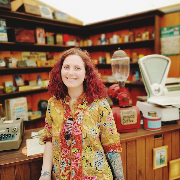 Foto retrato de una mujer sonriente de pie en la tienda