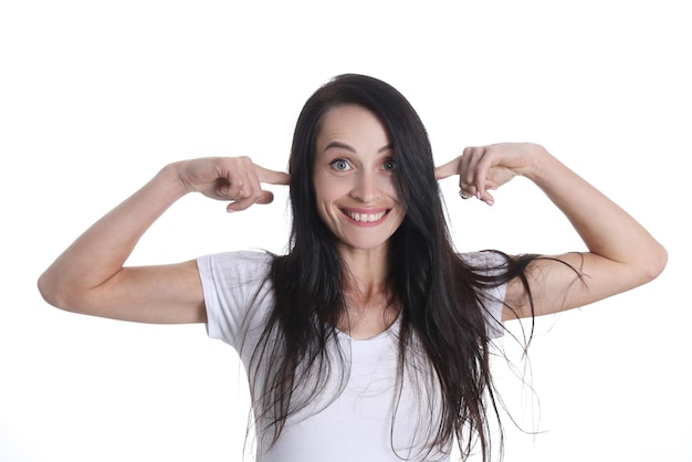 Foto retrato de mujer sonriente pone los dedos en los oídos emociones positivas y concepto de ruido extraño