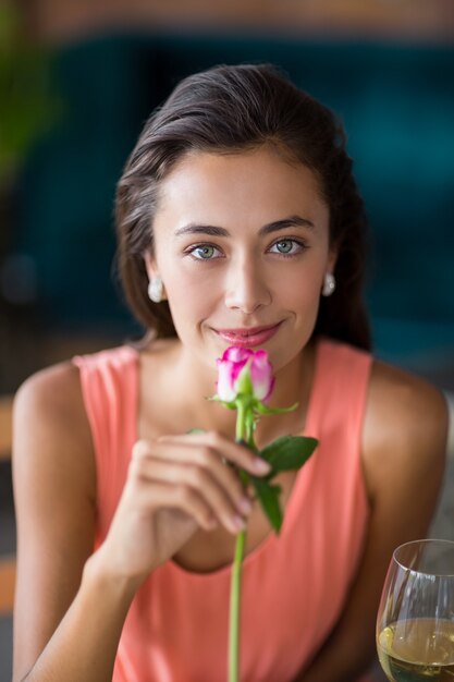 Retrato de mujer sonriente que huele una rosa