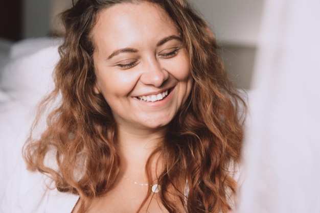 Retrato de mujer sonriente que se queda en casa y cierra los ojos de placer