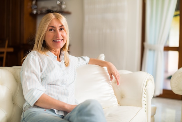 Retrato de una mujer sonriente que se relaja en el sofá de su casa