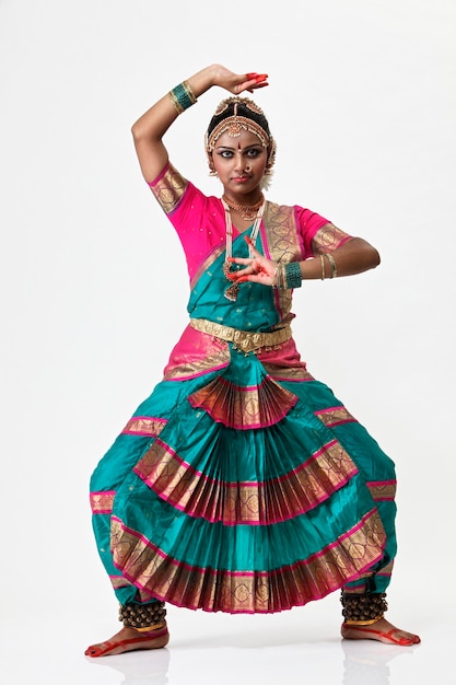 Retrato de una mujer sonriente realizando bharatnatyam contra un fondo blanco