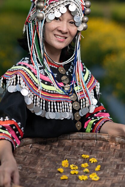 Retrato de una mujer sonriente con ropa tradicional sosteniendo una canasta de paja de pie en una granja