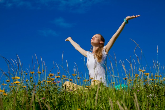 Retrato de mujer sonriente sentada al aire libre con las manos levantadas y regocijándose bajo el sol