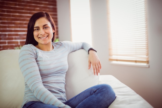 Retrato de mujer sonriente sentada en el sofá