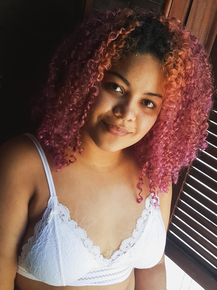Foto retrato de una mujer sonriente con sostén de pie en casa