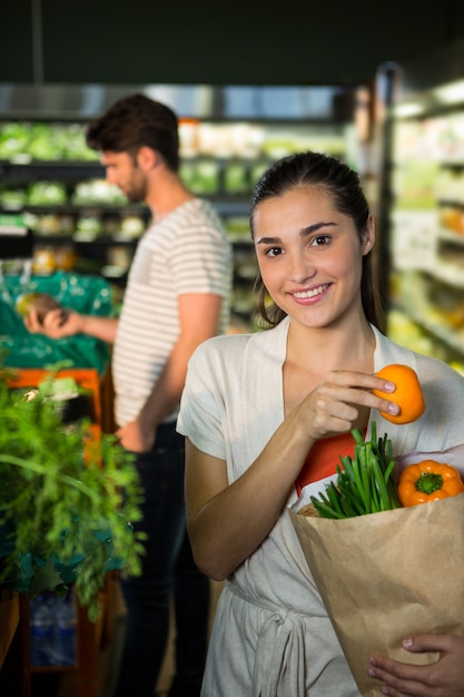 Retrato de mujer sonriente sosteniendo una bolsa de supermercado en la sección orgánica