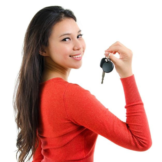 Foto retrato de una mujer sonriente sosteniendo la llave del coche contra un fondo blanco