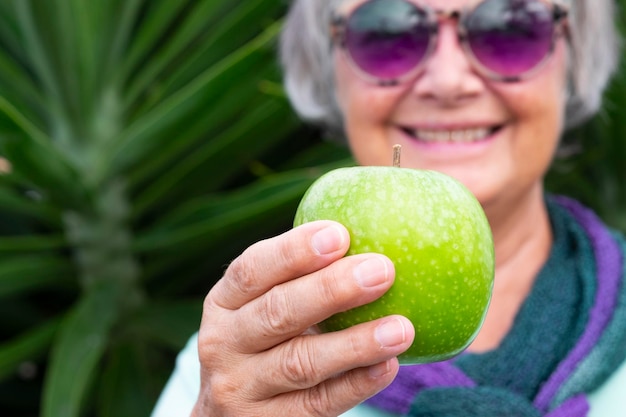 Foto retrato de una mujer sonriente sosteniendo una manzana mientras está de pie al aire libre.