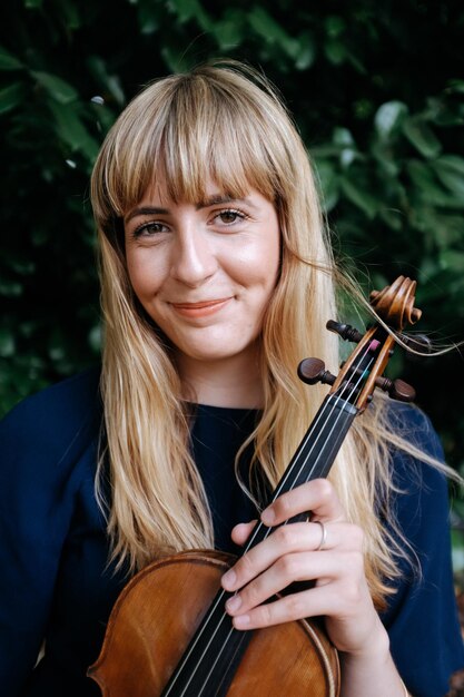 Retrato de una mujer sonriente sosteniendo un violín