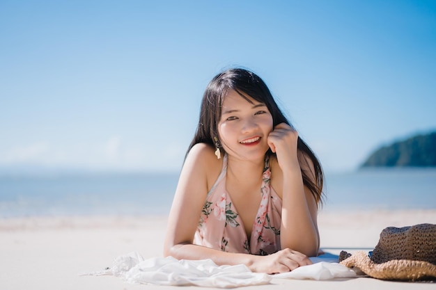 Retrato de una mujer sonriente tendida en la playa contra el cielo