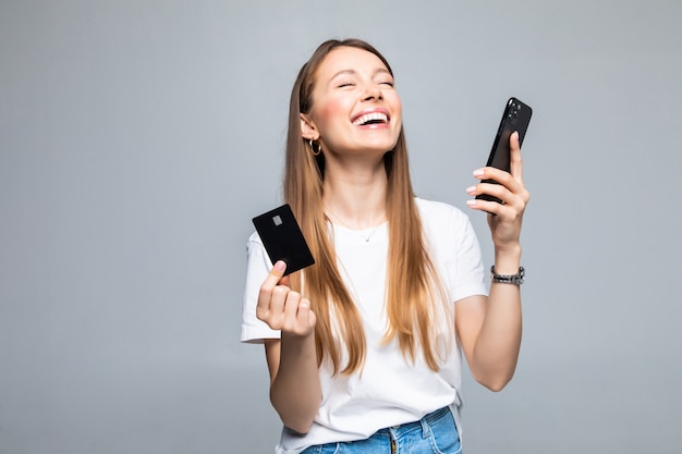 Retrato, de, un, mujer sonriente, tenencia, tarjeta de crédito, y, teléfono móvil