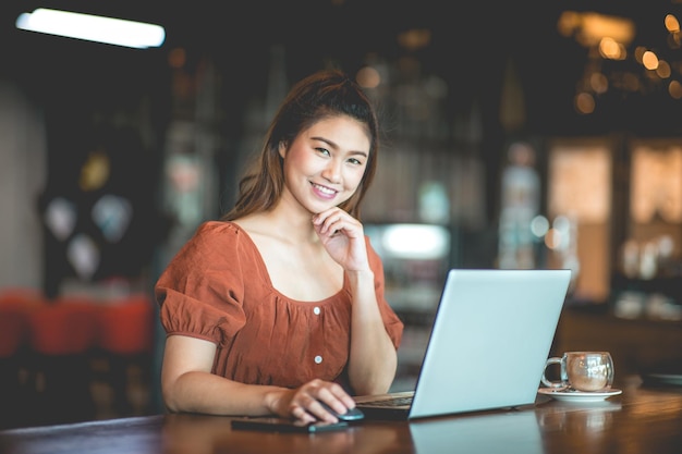 Retrato de una mujer sonriente usando una computadora portátil en un café