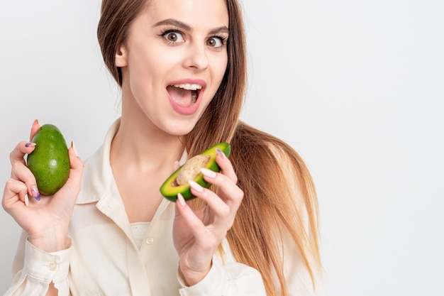 Retrato de mujer sorprendida con dos aguacate sobre fondo blanco con espacio de copia