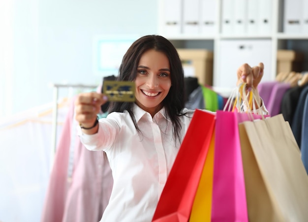 Retrato de mujer sosteniendo bolsas de compras en la tienda con tarjeta de crédito bancaria Descuentos y ventas favorables en compras