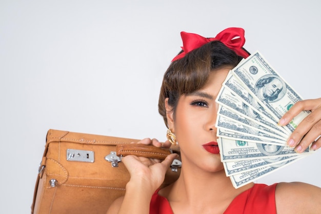 Foto retrato de una mujer sosteniendo un bolso y dinero contra un fondo blanco